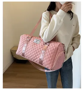 Close-up of a pink quilted duffle bag carried by a model for travel and fitness.