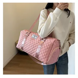 Large capacity pink quilted travel duffel bag carried by a model over the shoulder