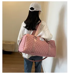 Woman carrying a pink quilted duffel bag, showing its large capacity and stylish design.