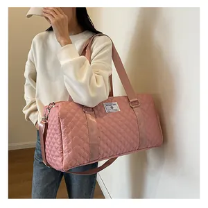 Detailed view of a stylish pink quilted duffel bag being used as a shoulder travel bag.