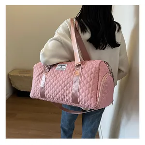 Pink quilted duffle bag for travel or gym shown carried by a person in detail