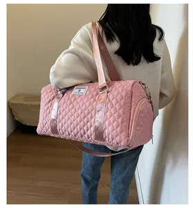 Pink quilted large capacity travel duffel bag carried by a person in a white sweatshirt
