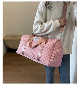 Pink quilted large capacity travel duffel bag held by a model in a casual setting