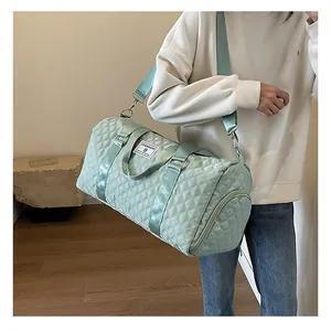 Large mint green quilted travel duffel bag shown carried for gym and short trips