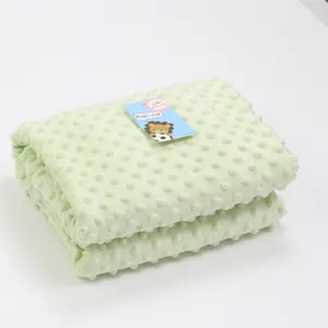 Soft light green minky dot baby blanket with embossed texture detail and brand tag