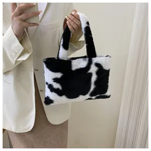 Model carrying a cute black and white cow print plush handbag with faux fur texture