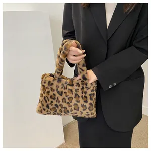 Close-up of leopard print plush handbag held by a woman in a black blazer