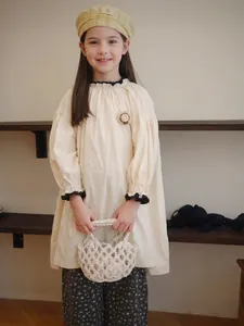 Vista dettagliata di una borsa in macramè crema tenuta da un bambino in stile vintage