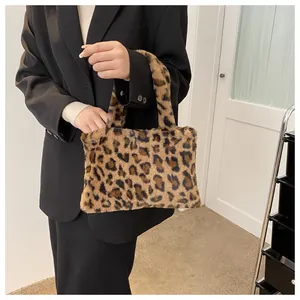 Detail shot of the leopard print faux fur handbag held by a model in a black blazer