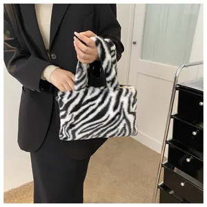 Close-up of zebra pattern plush handbag held by a model in a stylish outfit