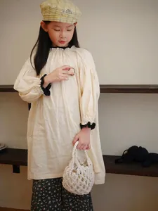 Vista dettagliata di una borsa in paglia intrecciata bianca tenuta da una ragazza in abito