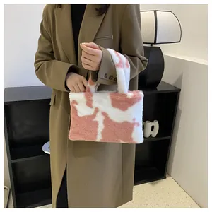 Fashionable pink and white cow pattern plush tote bag being held by a model in a stylish blazer