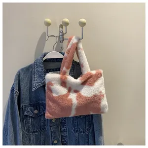 Detail view of a cute pink and white plush cow print handbag hanging on a hook.