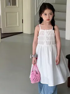 Primo piano di una mini borsa rosa intrecciata tenuta da una bambina con un abito bianco