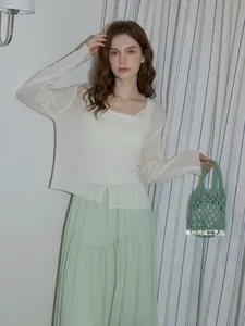 Donna alla moda con un'elegante borsa tote verde all'uncinetto fatta a mano traforata.