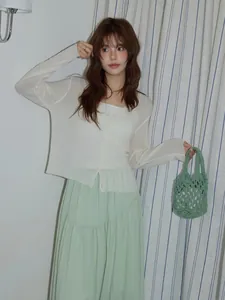 Mujer elegante sosteniendo un bolso tote de ganchillo verde hecho a mano con diseño calado.