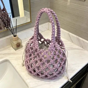 Primo piano di borsa a mano viola lavorata all'uncinetto con sacchetto interno grigio