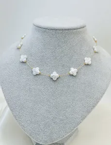 Detailed close-up of an elegant white clover shell necklace on gold chain jewelry