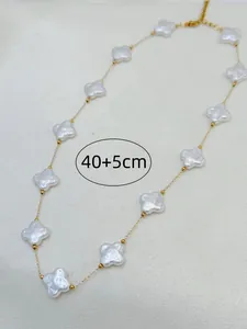 Detail view of a gold clover necklace with white shell elements and 40+5cm length.