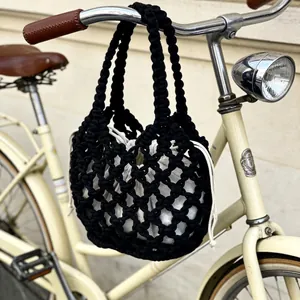 Elegante borsa a mano in macramè nero con custodia interna bianca su una bicicletta d'epoca