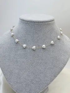 Detailed shot of elegant gold chain necklace with white heart-shaped pearl beads.