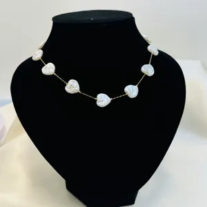Detailed view of iridescent heart-shaped shell elements on a delicate gold chain.