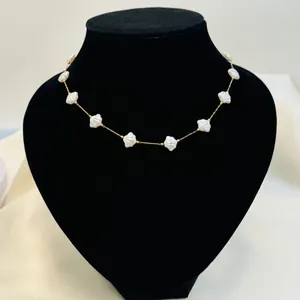 Close-up detail of a delicate gold chain necklace featuring elegant white shell beads.
