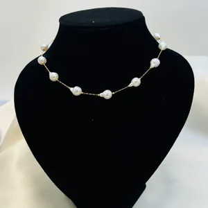 Elegant gold chain necklace with irregular white baroque pearl beads on black display
