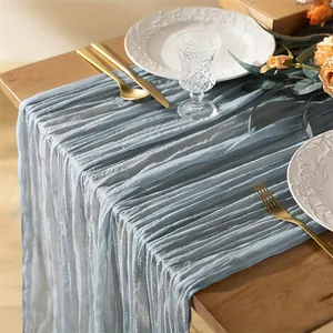 Eleganter tischläufer aus staubblauem gaze-stoff mit plissierter textur für hochzeiten.