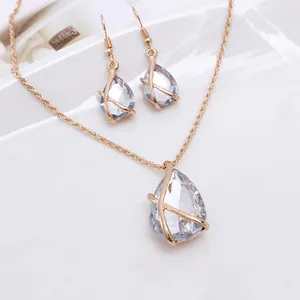 Close-up of elegant gold-toned necklace and earrings set with water-drop crystal pendants