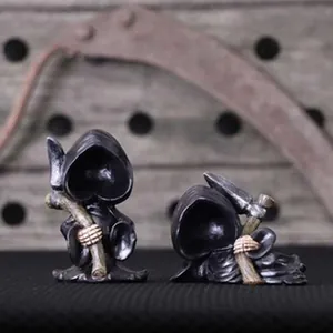Macro detail of miniature grim reaper resin figurines featuring heart-shaped hood faces