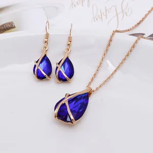 Close-up of blue teardrop gemstone necklace and earring set with gold hollow frames.