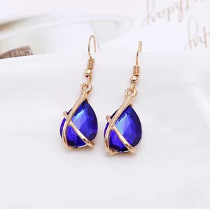 Close-up of elegant gold earrings with blue teardrop-shaped crystal gems