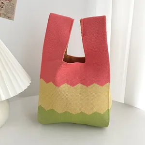 Primo piano di una borsa a mano in maglia colorata con motivi a zig-zag su un tavolo