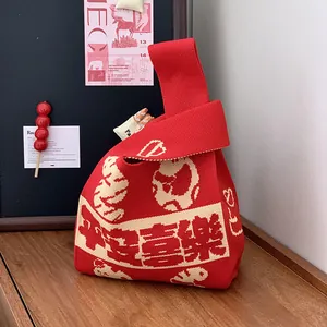 Dettaglio di una borsa a nodo in maglia rossa con caratteri e motivi cinesi di buon auspicio