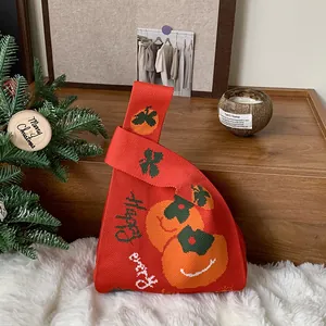 Dettaglio borsa in maglia rossa con motivi festivi arancioni e scritta Happy
