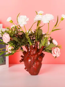 Close-up detail of a creative anatomical heart-shaped resin flower vase in red color