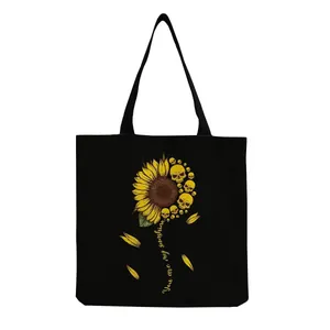 Detailed view of black canvas tote bag featuring artistic sunflower and skull print