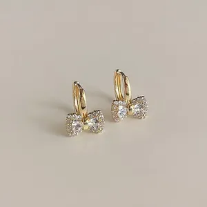 Elegant golden bow-knot hoop earrings with full clear rhinestone pavé setting.