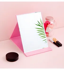 Portable pink folding makeup mirror with premium leather stand on a pink background.