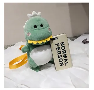 Detail view showing size comparison of cute green plush dinosaur bag next to a phone