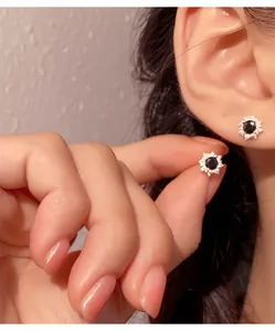 Detailed view of black gemstone floral ear studs in silver, shown on a model's ear.