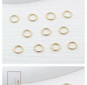 Macro shot of 14K gold-filled twisted jump rings with decorative texture for DIY jewelry.