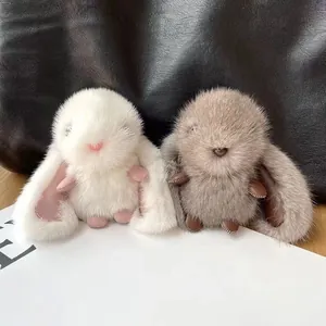 Close-up of two fluffy faux mink fur rabbit keychains with long ears in white and grey