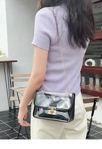 Primo piano di un'elegante borsa in PVC trasparente con catena d'oro indossata da modella