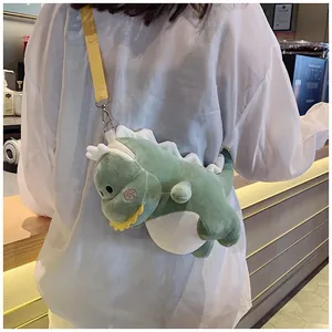 Cute green plush dinosaur crossbody bag worn by a person over a white shirt style