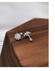 S999 silver snowflake stud earrings with sparkling cubic zirconia on wood