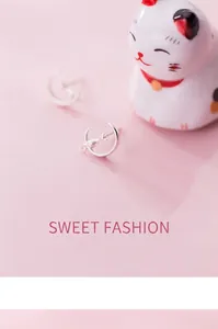 Close-up of S925 silver cat and crescent moon stud earrings on pink background