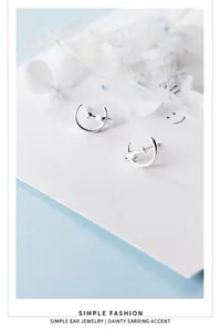 Macro detail showing S925 silver crescent moon and cat stud earrings on a white card.