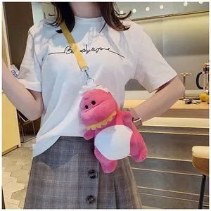 Detail shot of a cute pink dinosaur plush crossbody bag worn by a model.